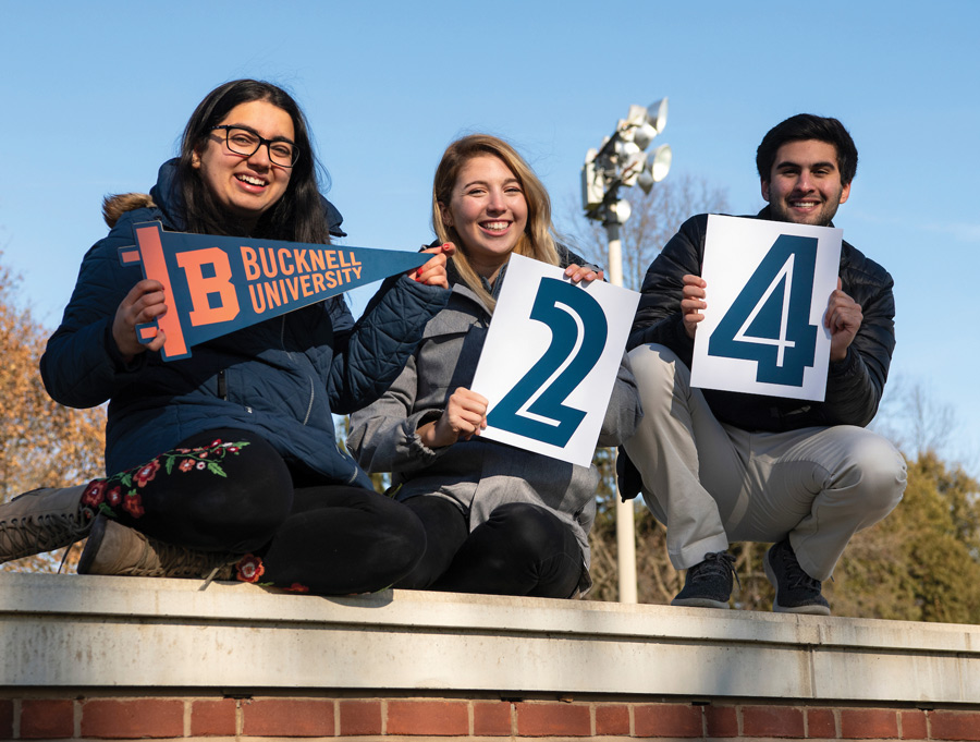 Bucknell students standing on a wall with spirit signs