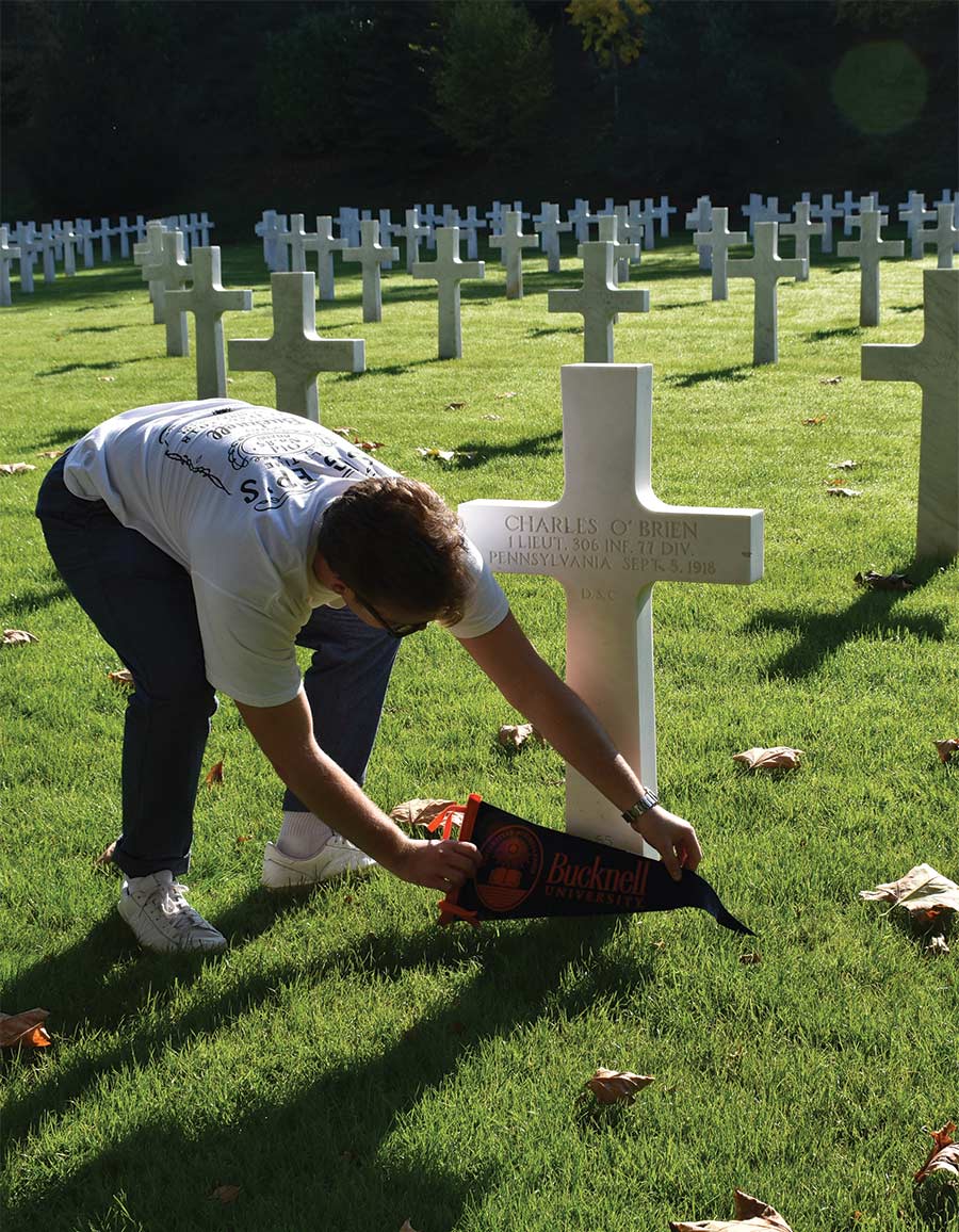 Peter Stokes ’21 places a pennant on a Bucknellian’s grave in France.