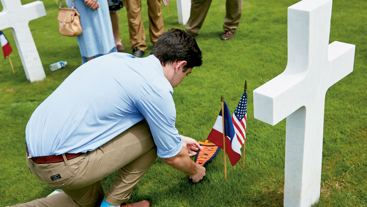 Student placing flags at a military headstone