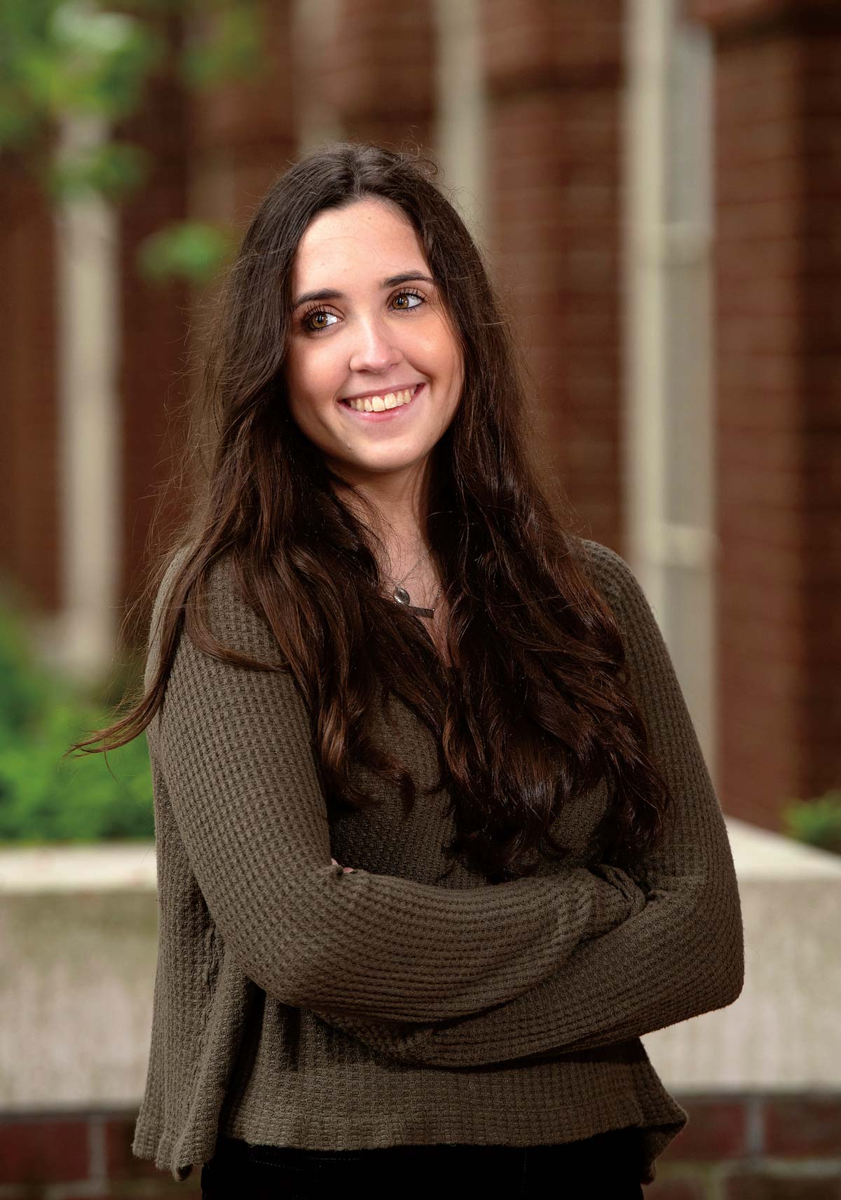 Portrait photo of Sara Micciulli ’23 smiling and looking away with crossed arms in a brown sweater