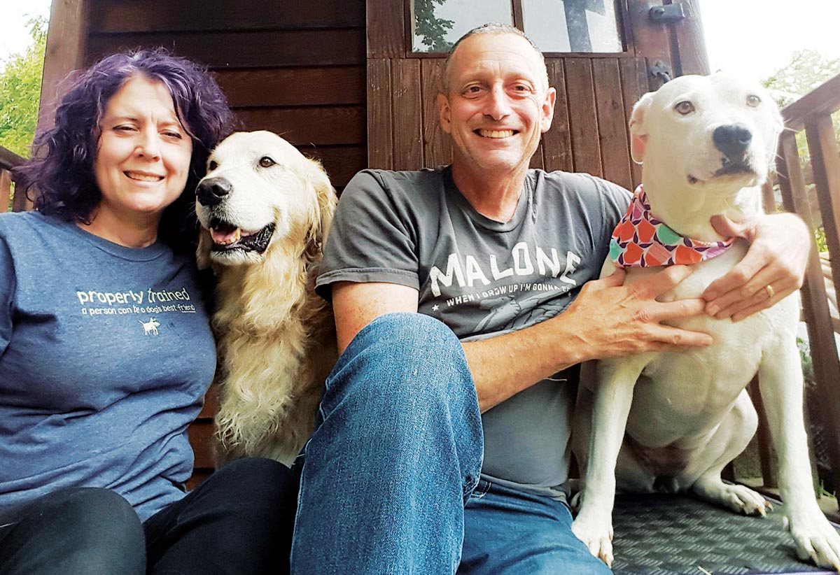 Matt and Kelly Bugle Elvin pictured smiling sitting with their two dogs
