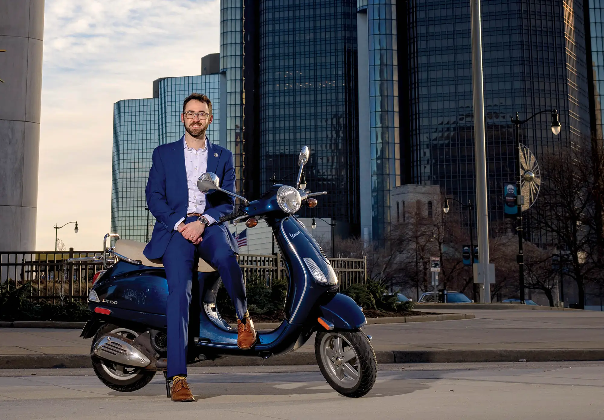 Sam Krassenstein on a parked motorbike wearing a suit
