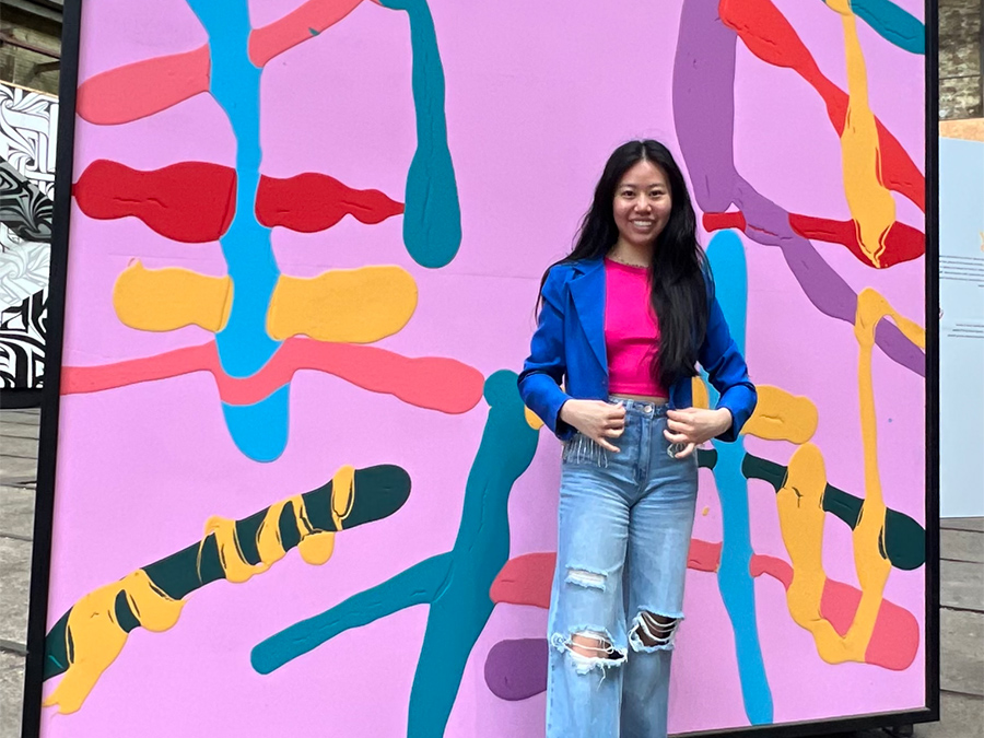 student in Amsterdam in front of bright pink wall with colorful paint splatters