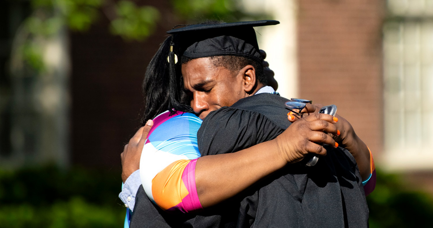 a grad and family member in a tight embrace