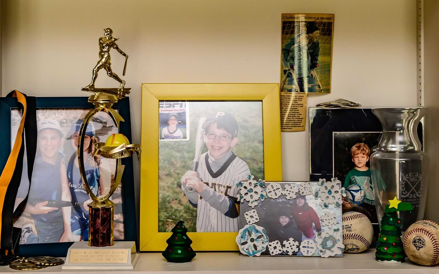view of a shelf in the Agostini home featuring images of the Agostini children participating in sports and activities
