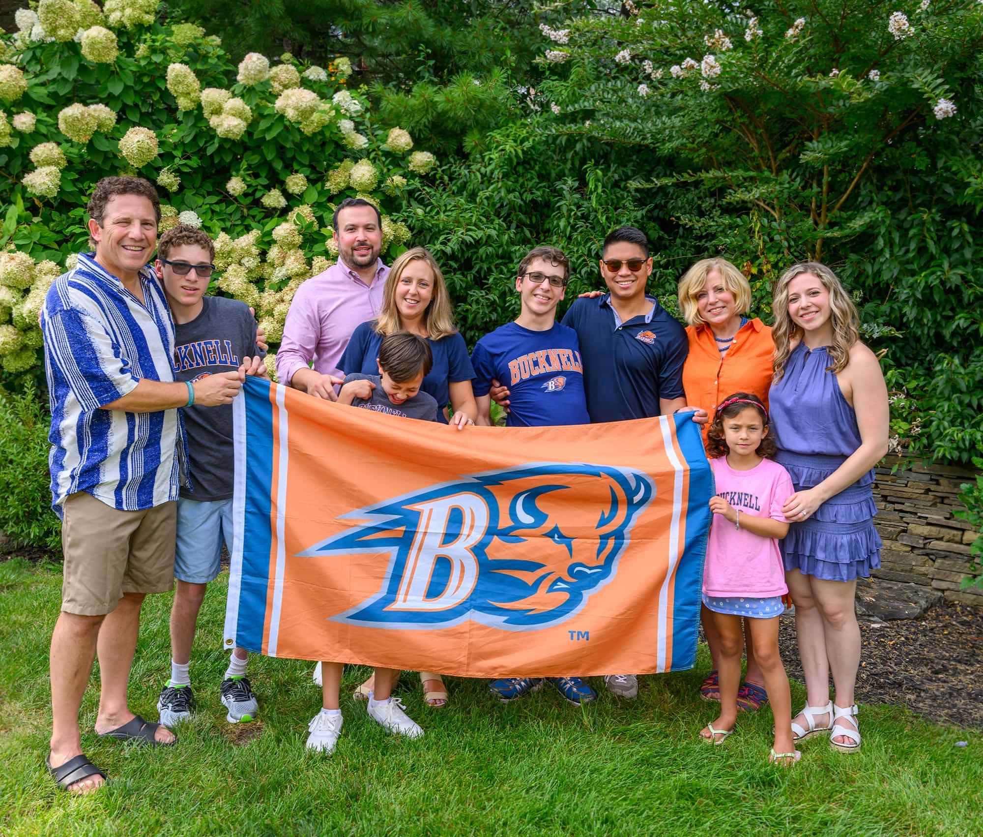 Gale and Agostini families photographed together while they all hold the Bucknell Bison flag