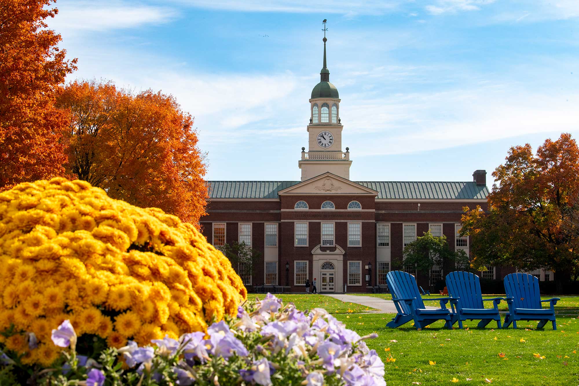 Bucknell courtyard with fall colored trees and three blue lawn chairs on grass
