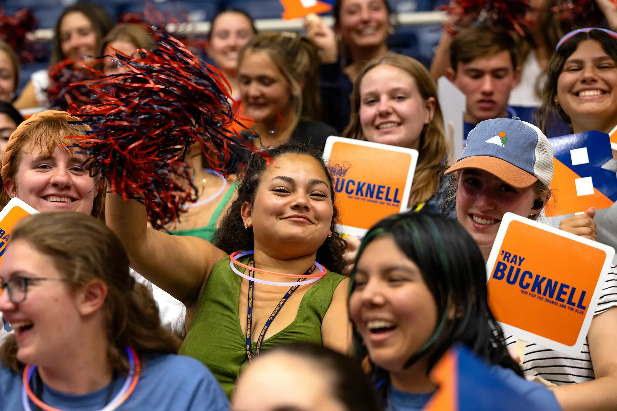 Student in crowd at orientation cheering with a pom-pom