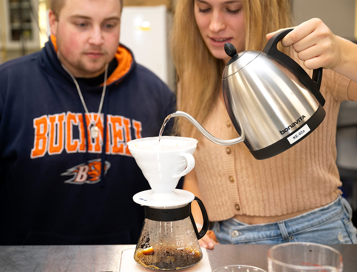 Bucknell students pouring hot water from an electric kettle into a coffee dripper