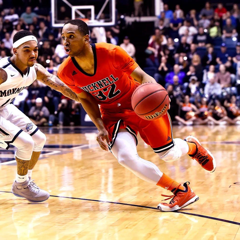 Ryan Frazier in a red Bucknell basketball jersey and dribbling a basketball