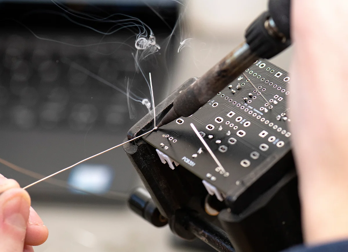 closeup of Thomas Smith soldering components of a guitar pedal together