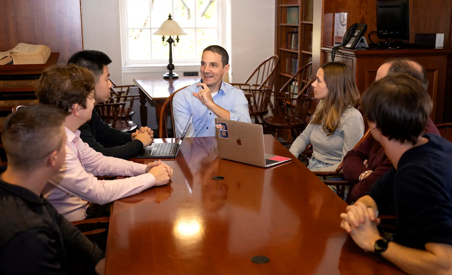 a small team of Bucknell faculty and students sit at a table in a library, holding a meeting