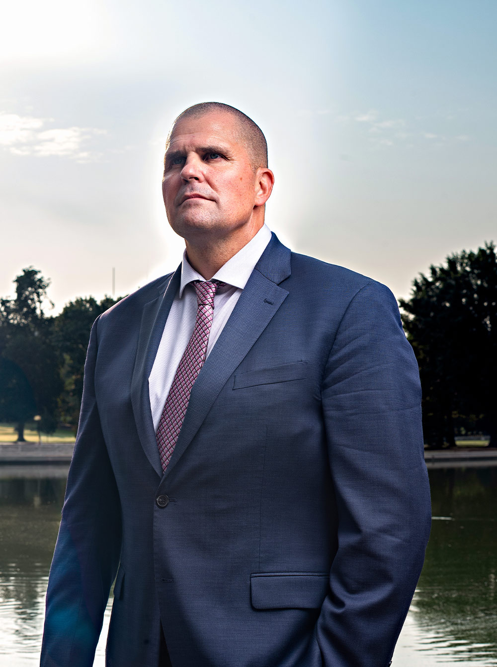 quarter view portrait of Ed Currie wearing a suit and standing against the Capitol Reflecting Pool