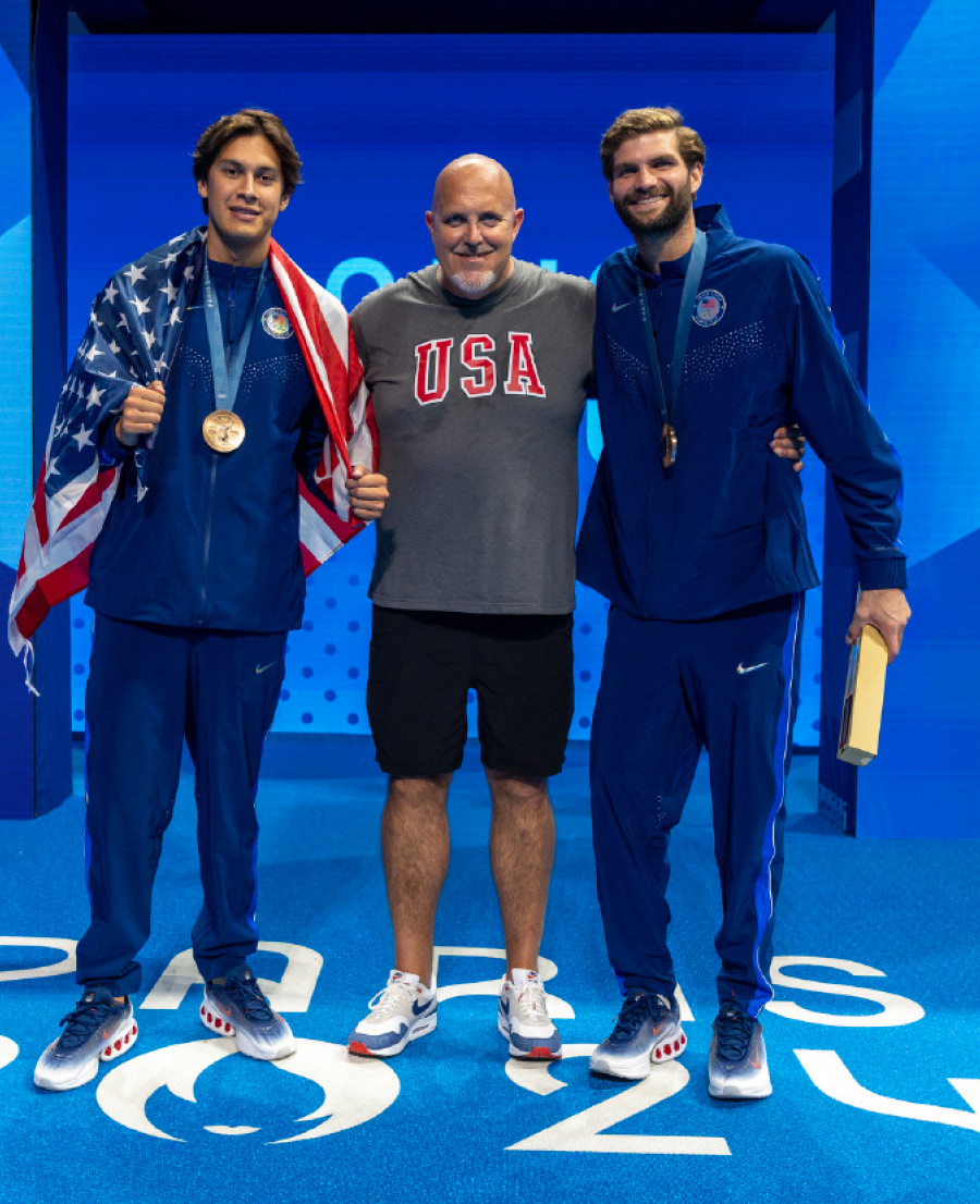 John McBride standing next to two men from his water polo team with medals