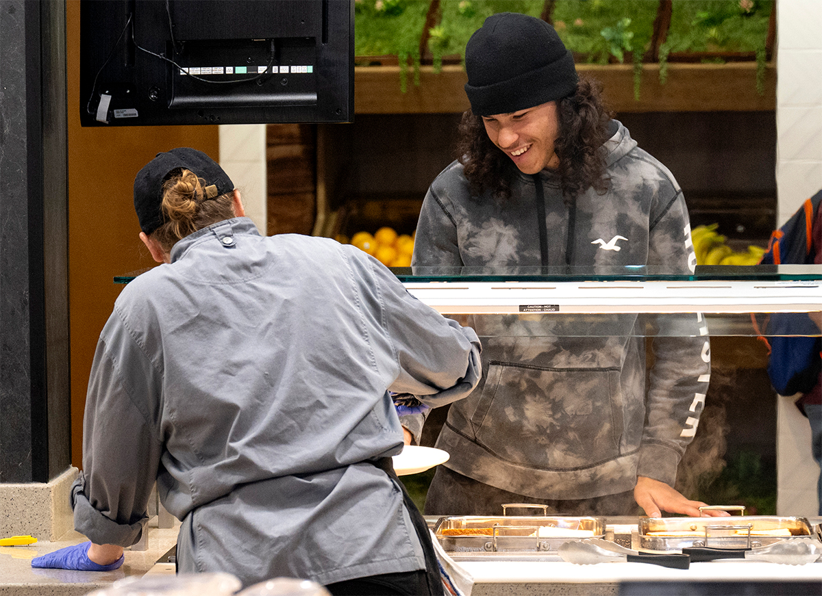 student interacting with a staff member at a campus dining hall counter