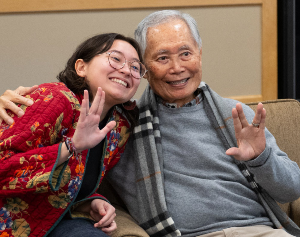 Two people posing for a photo while sitting on a couch.