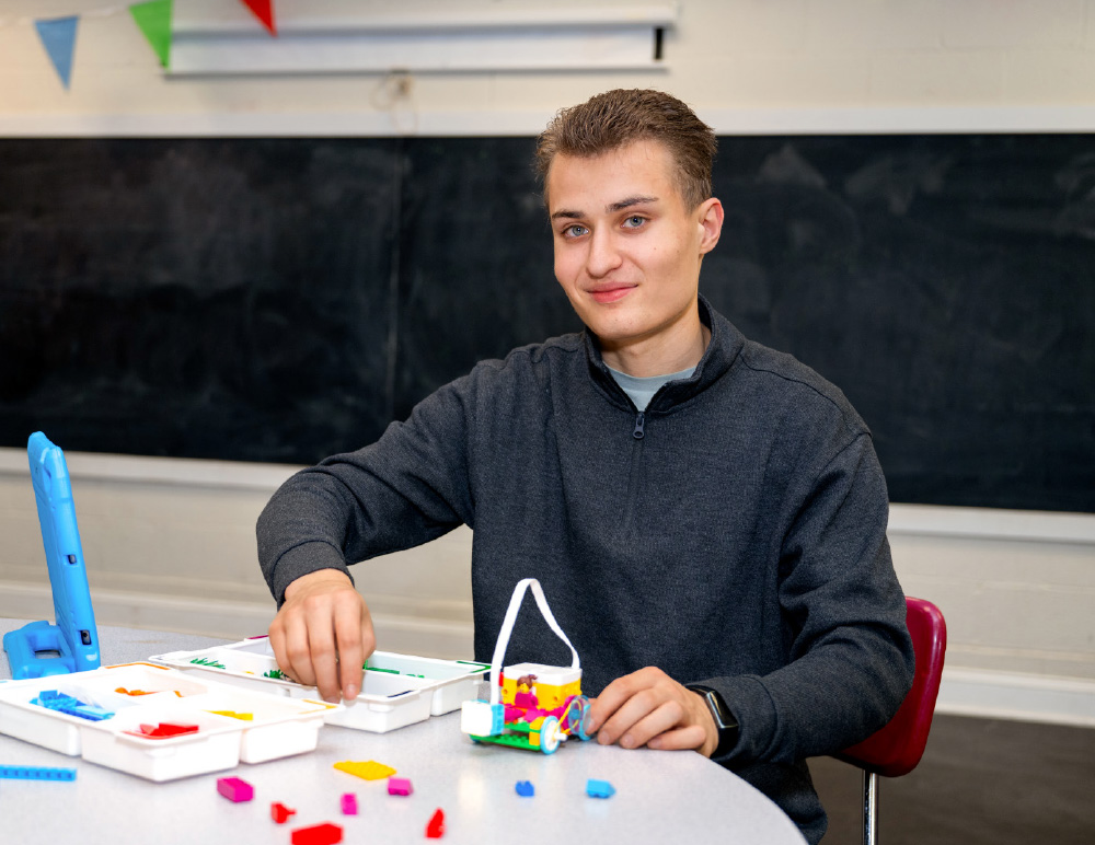 Aiden Cherniske seated at a table, working with colorful building blocks or small construction pieces.
