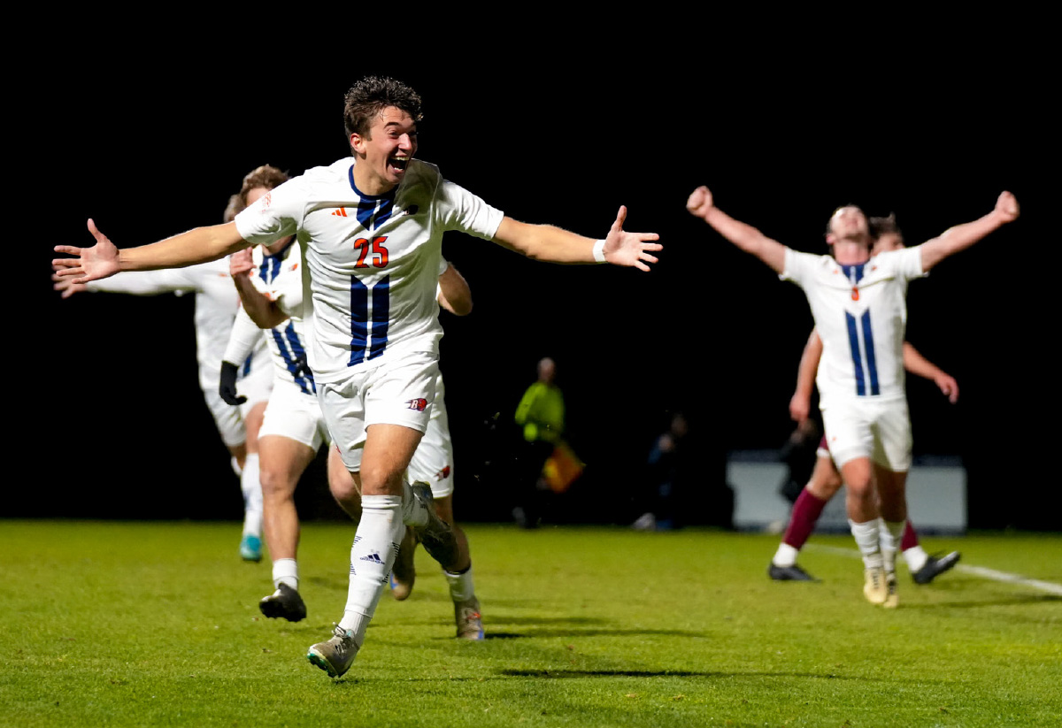 A group of soccer players in white athletic uniforms with blue stripes celebrating
