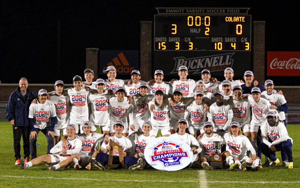 Soccer team group photo in front of scoreboard.