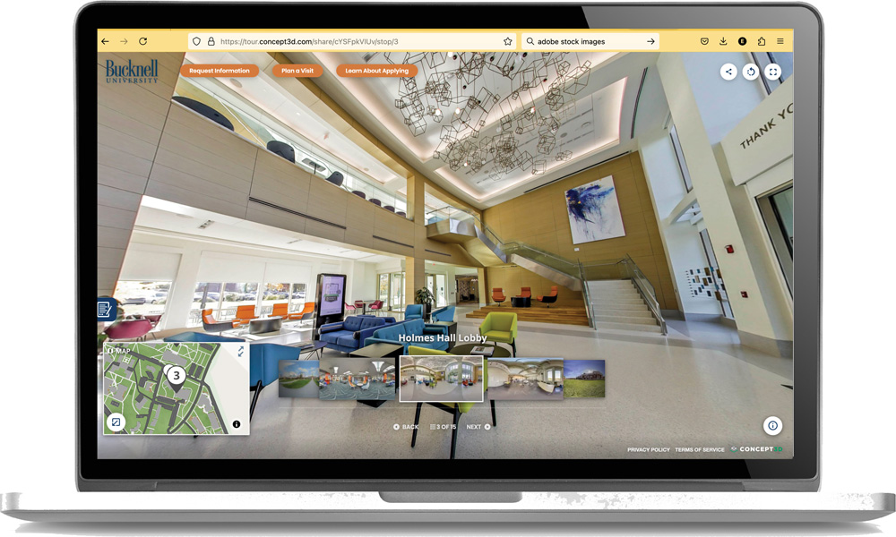 Laptop displaying a virtual tour of a modern lobby with seating area, stairs, and pendant lights.