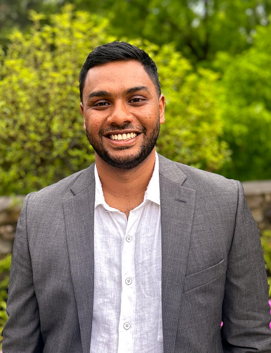 portrait image of Uttam Kumaran ’18 wearing a grey suit jacket and a linen dress shirt